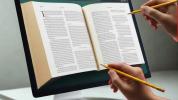 due matite puntano a un libro inscritto in uno schermo di computer